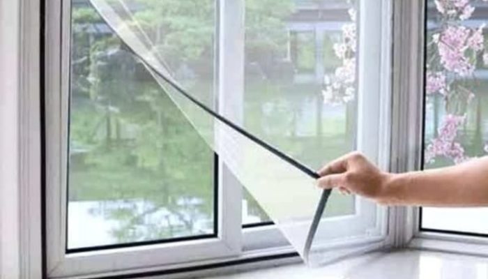 A fine mesh mosquito net installed on a window frame, showing a clear view outside.